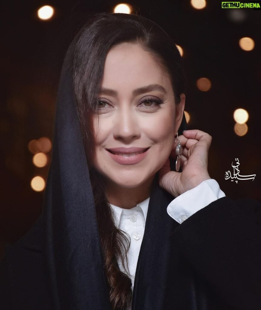 persian model with long dark hair wearing a white lace dress looking into camera