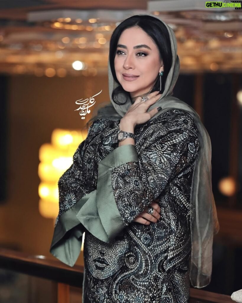 persian model with long dark hair wearing a white lace dress looking into camera