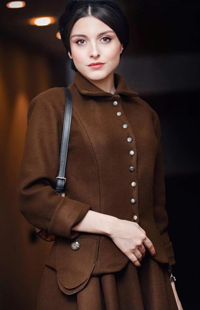 persian actress with long dark hair wearing a burgundy velvet dress looking into camera