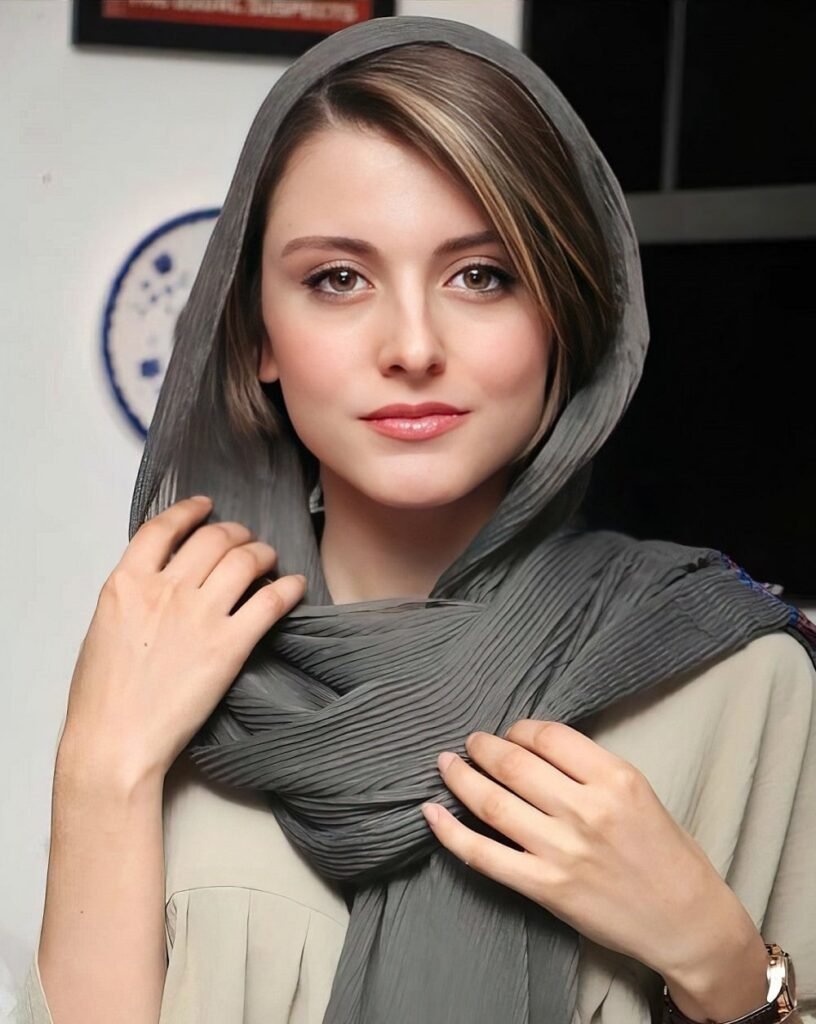 persian actress with long dark hair wearing a cream-colored lace top posing in soft natural light