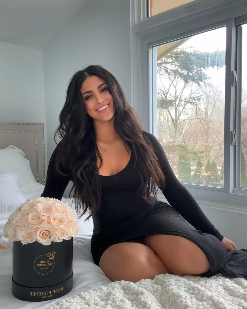 persian model with long dark hair wearing a pink summer dress posing in a garden setting