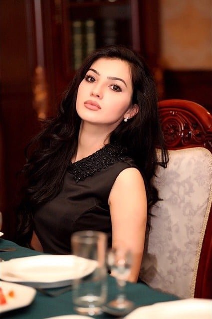 persian model with long dark hair smiling while wearing a white tank top