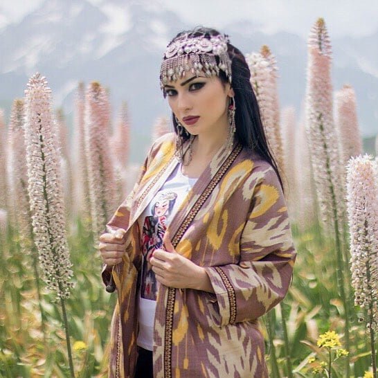 persian model with long dark hair smiling while wearing a white tank top