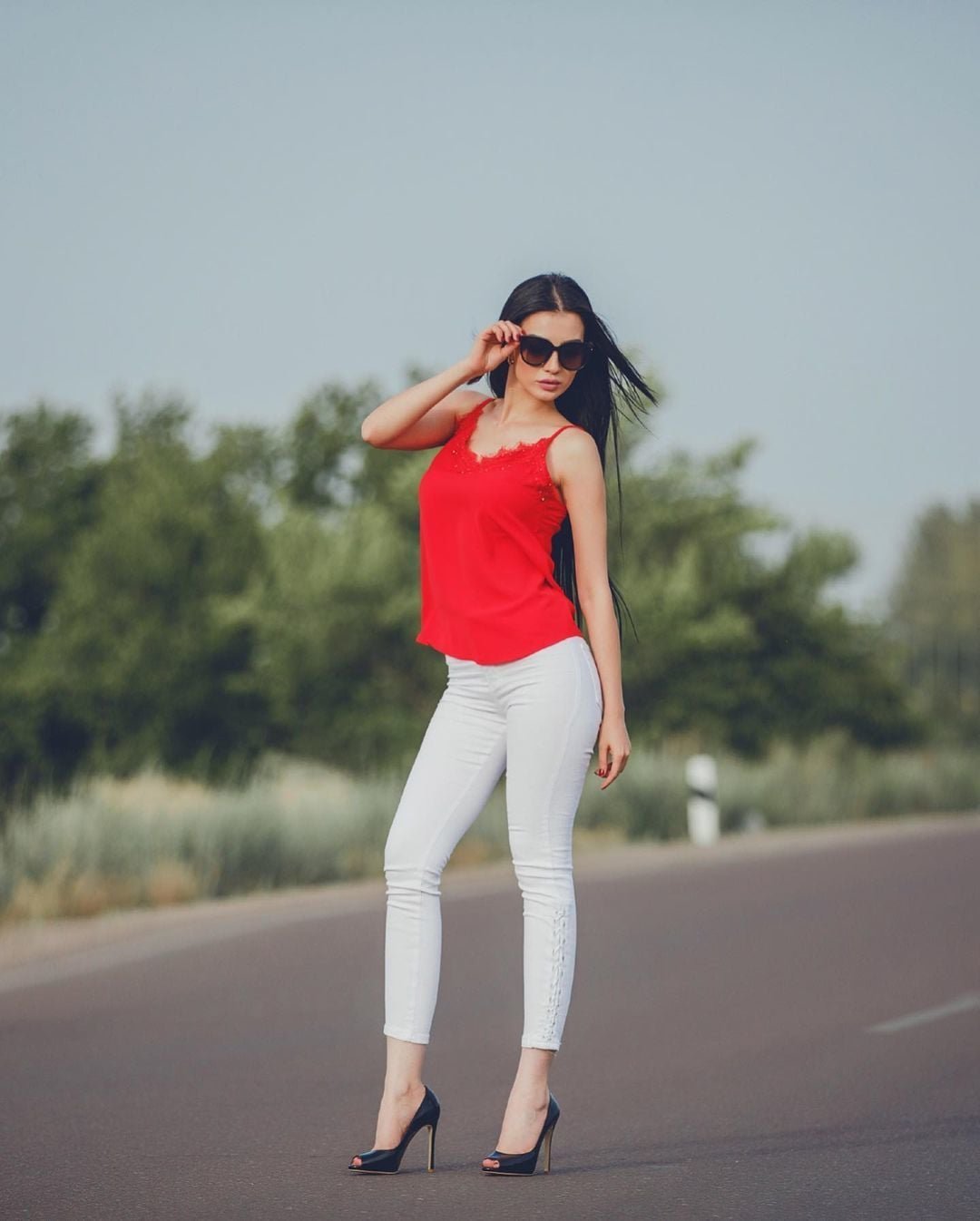 persian model with long dark hair looking into camera wearing a white tank top