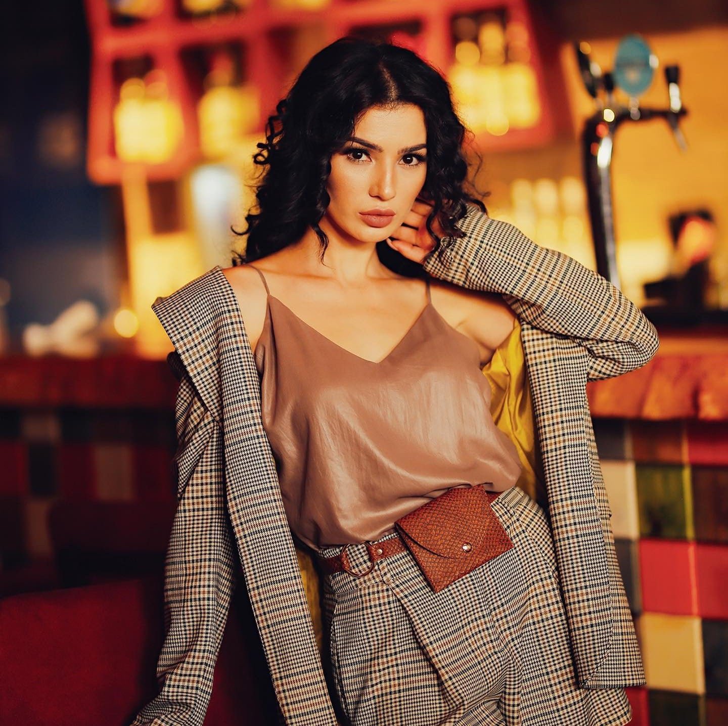 persian model with long dark hair looking into camera wearing a white tank top