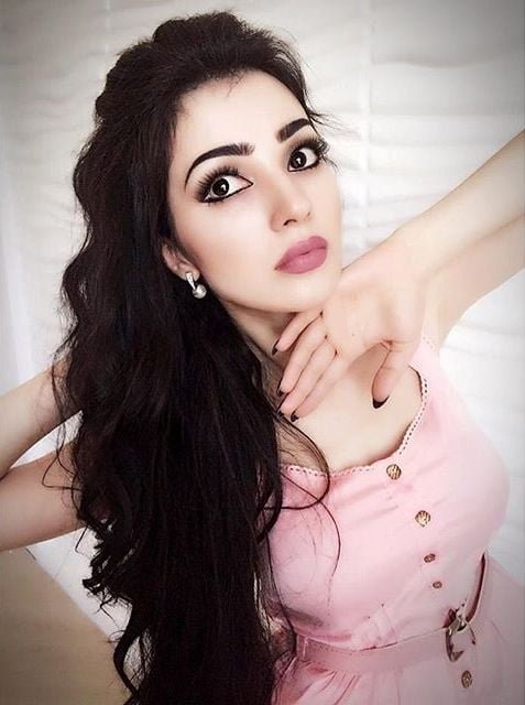 persian model with long dark hair looking at camera wearing a white crop top