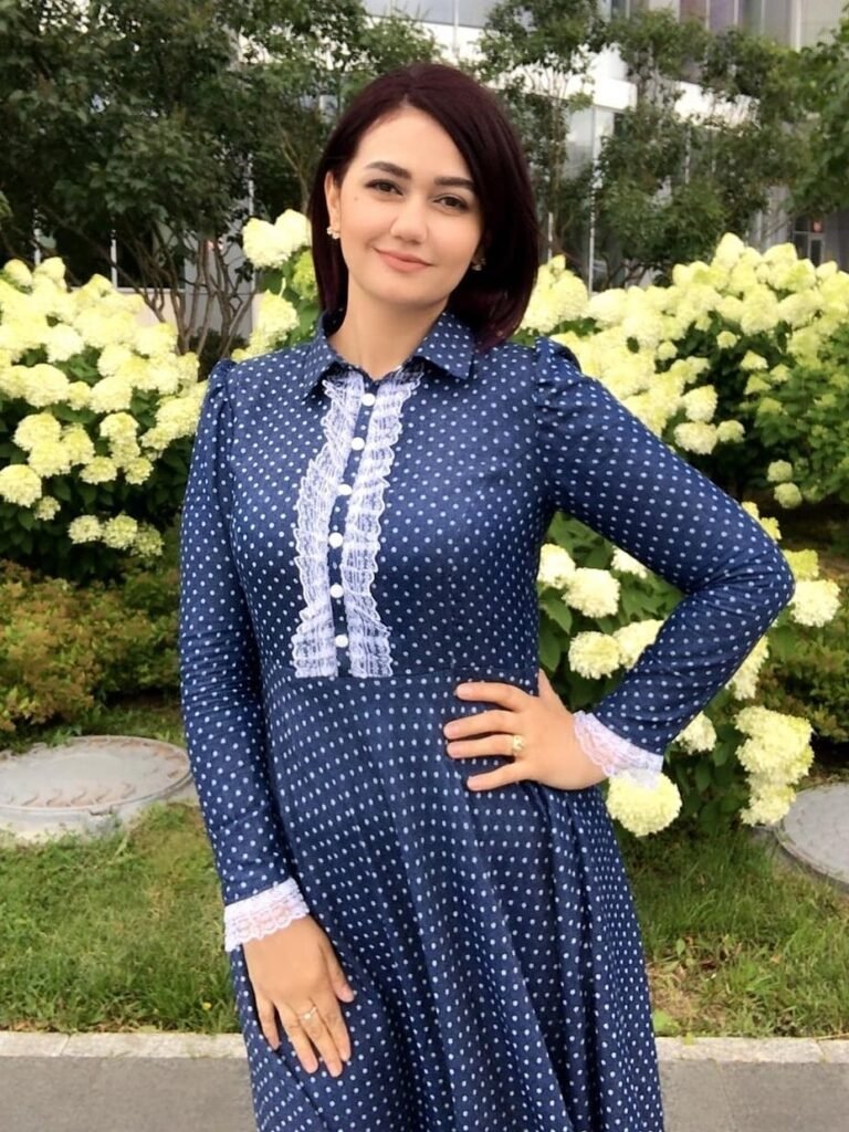 persian model with long dark hair looking into camera wearing a black top and silver earrings