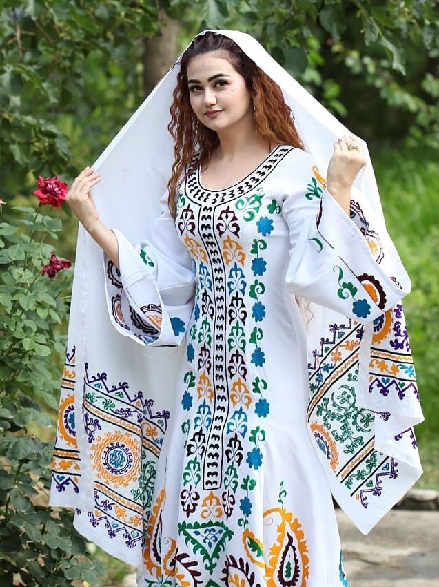 persian model with long dark hair smiling while looking into camera wearing a black top and silver earrings