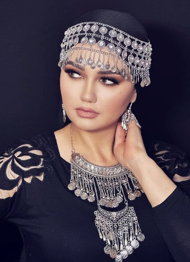 persian model with long dark hair looking into camera wearing a black top and silver earrings